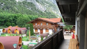 A wooden building with a balcony, surrounded by a garden and yurts. - Gasthof Rafting Alm (Haiming)