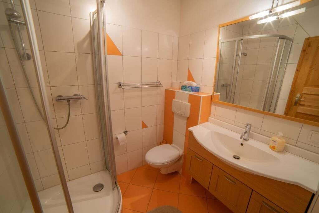 A bathroom with a shower, toilet, sink, and mirror.