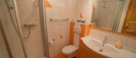 A bathroom with a shower, toilet, sink, and mirror.