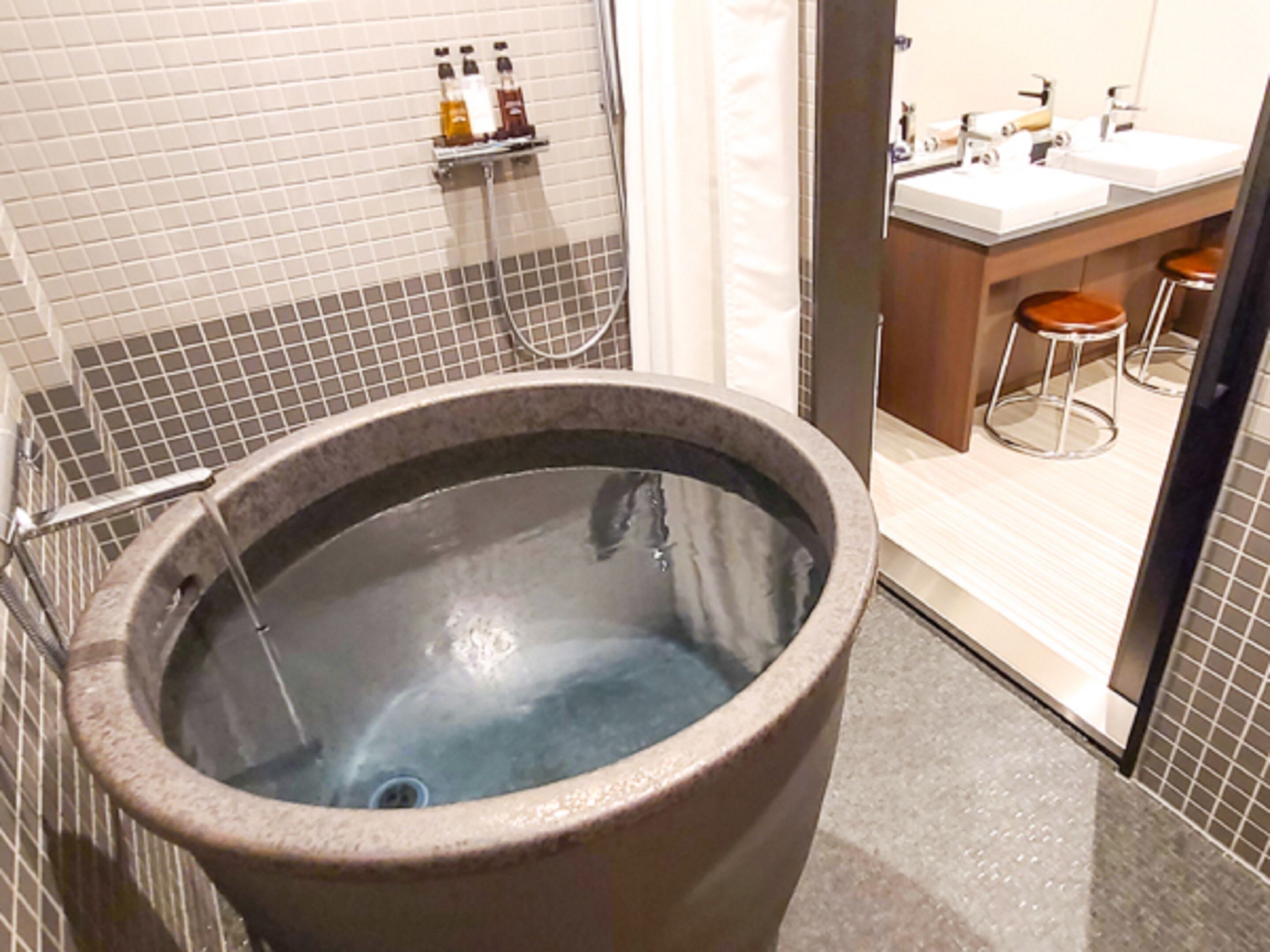 A spa area with a large soaking tub, a shower area, and a vanity with two sinks and stools.