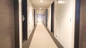 A long, narrow hotel corridor with doors on both sides, numbered 212, leading to individual rooms. - Hotel LiveMax Akasaka Grande (Tokyo)