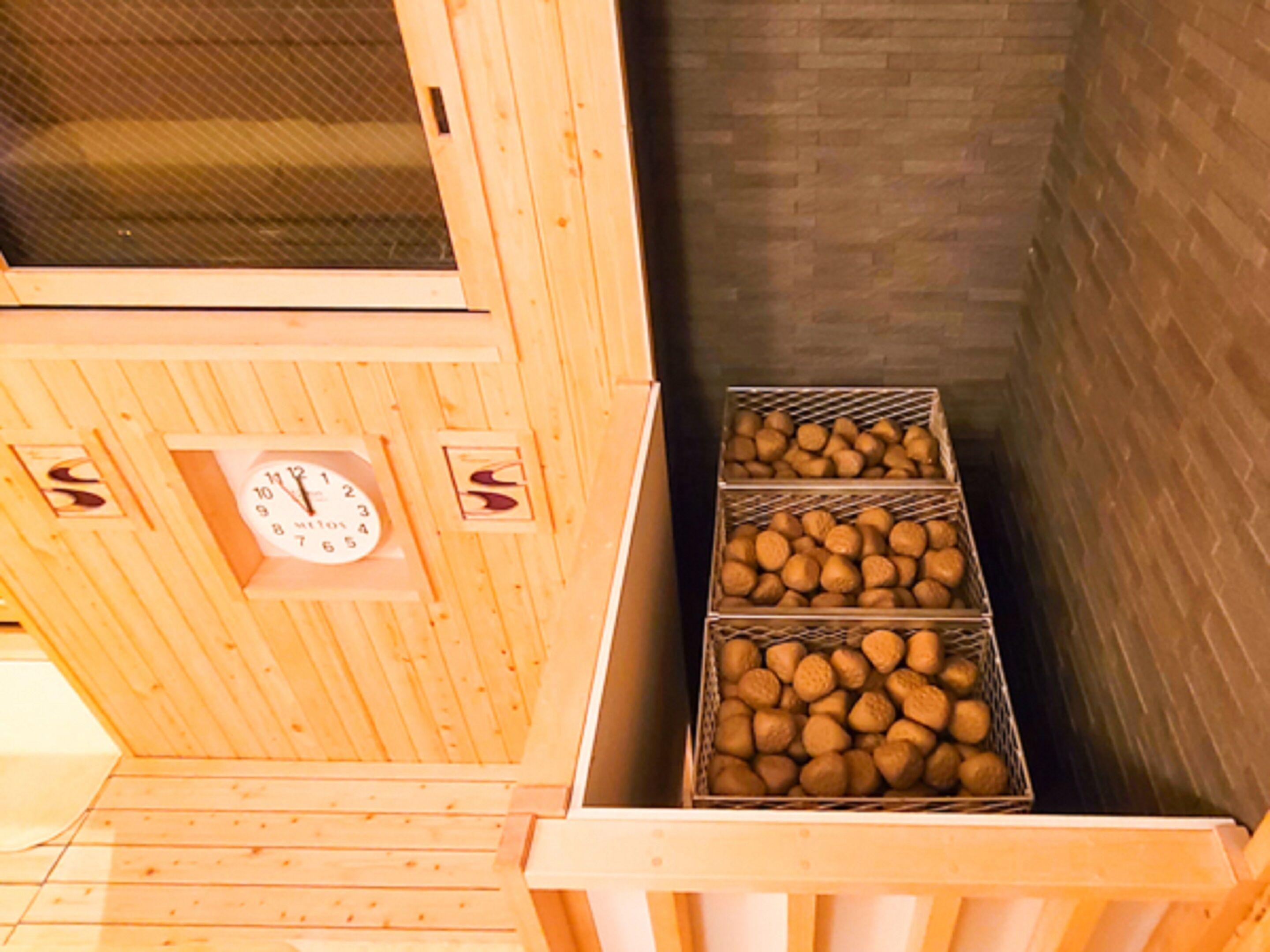 A wooden interior with a clock and three metal baskets of nuts.