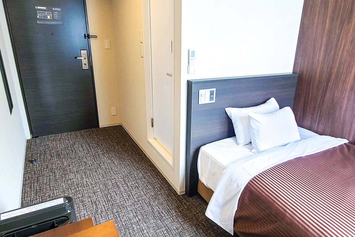 Una habitación de hotel con cama, escritorio y puerta.