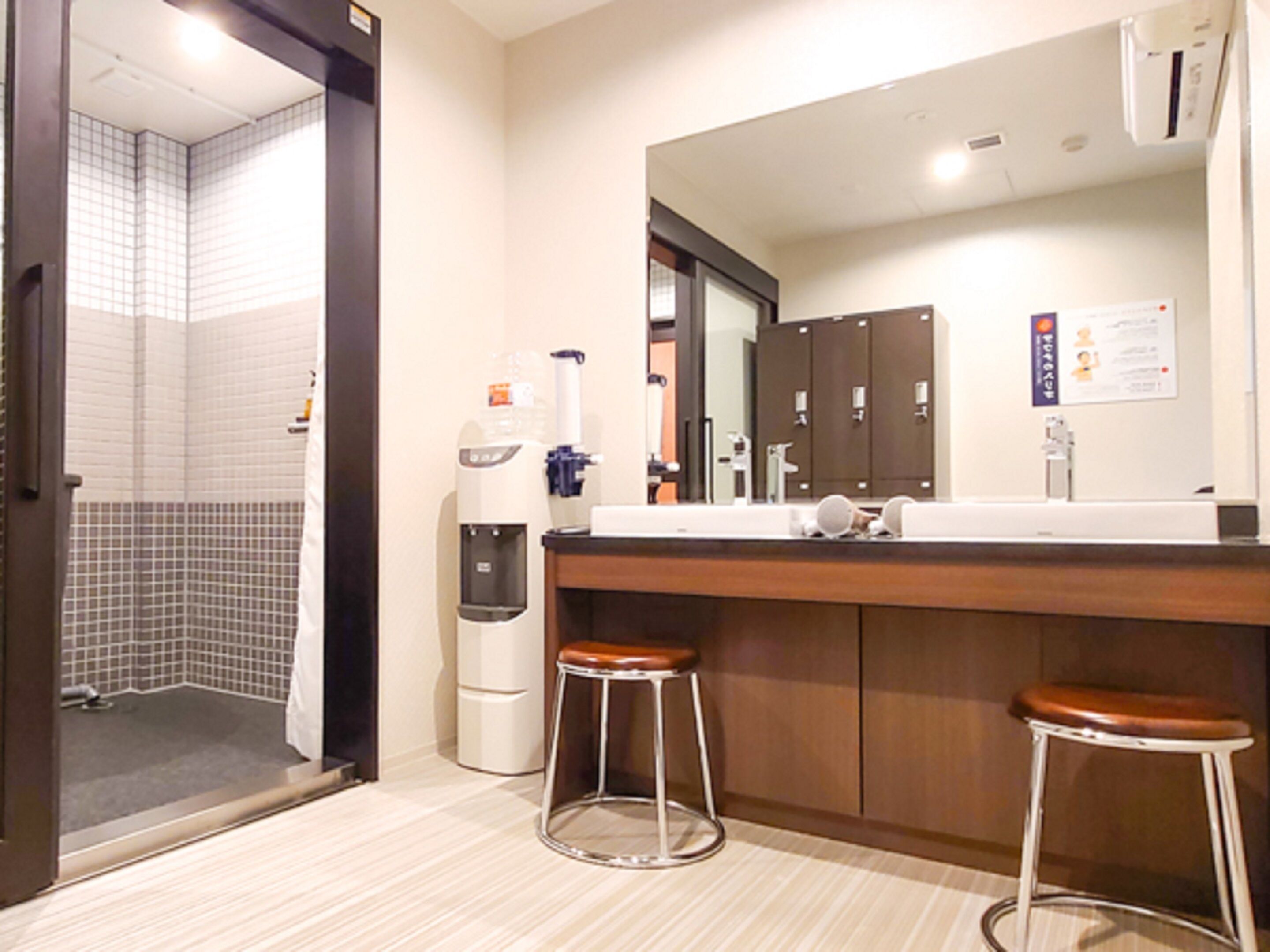 A modern bathroom with a shower, a coffee machine, and a mirror above the sink.