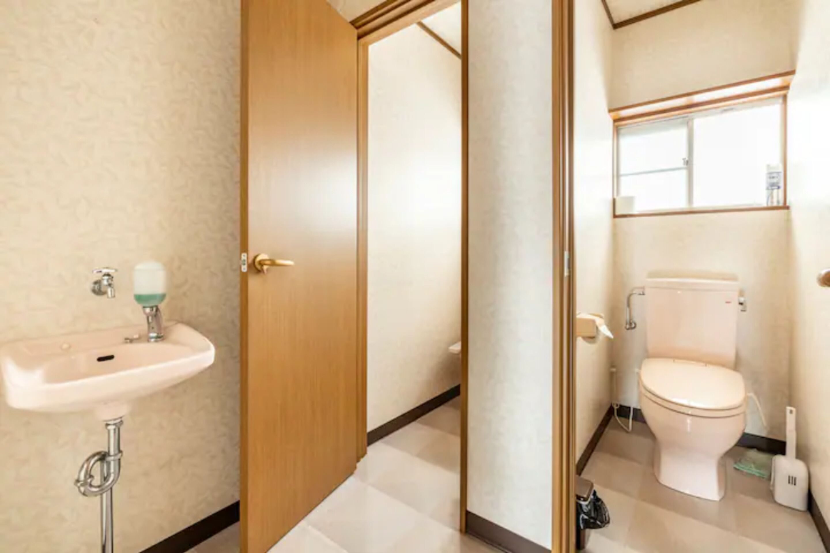 A bathroom with a wooden door, a white sink, and a toilet.