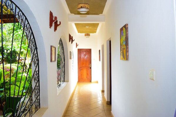 A hallway with a wooden door, tiled floor, and decorative wall art.