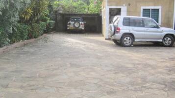 Um caminho de paralelepípedos leva a um edifício, onde se vê um SUV e um carro estacionados.
