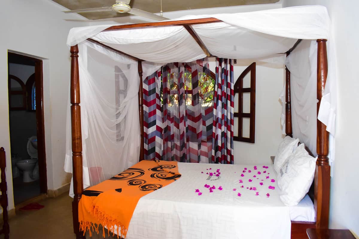 Un lit à baldaquin, une couvre-lit à motifs et un coussin décoratif.