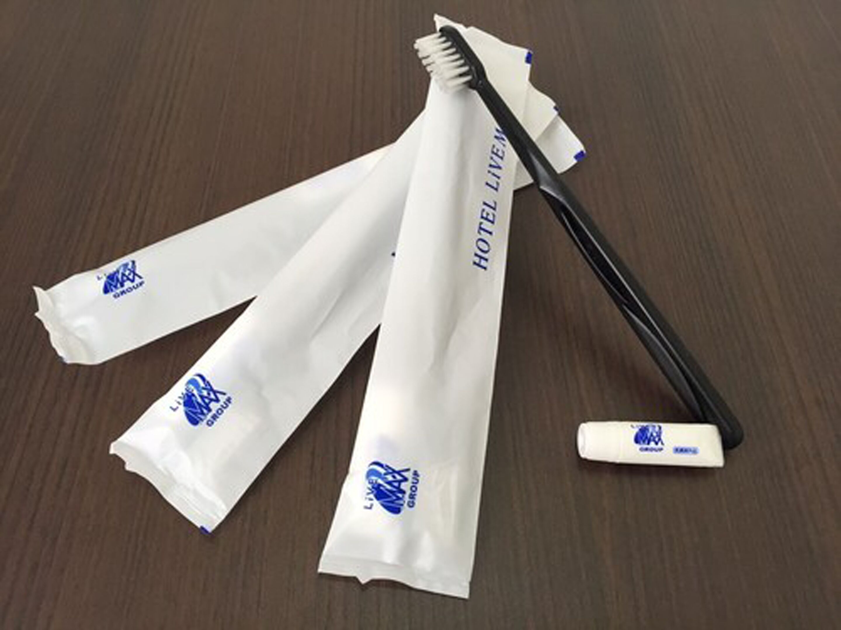 A toothbrush, a tube of toothpaste, and a pair of white socks with blue logos on a wooden surface.