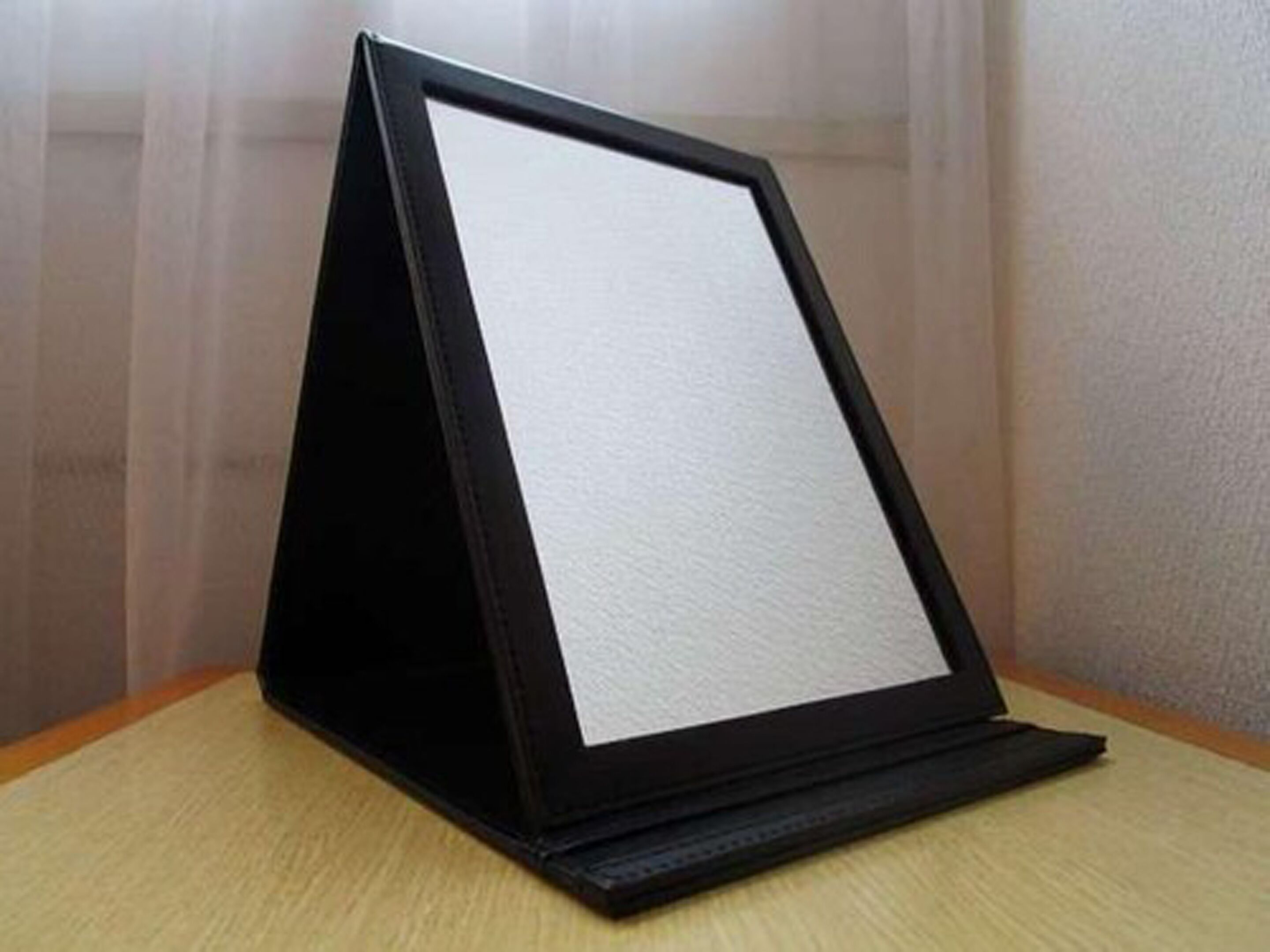 A black standee with a white background, placed on a wooden surface against a plain wall.