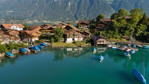 A lakeside village with traditional houses, boats, and a mountain backdrop. - Lake Lodge Hostel (Iseltwald)