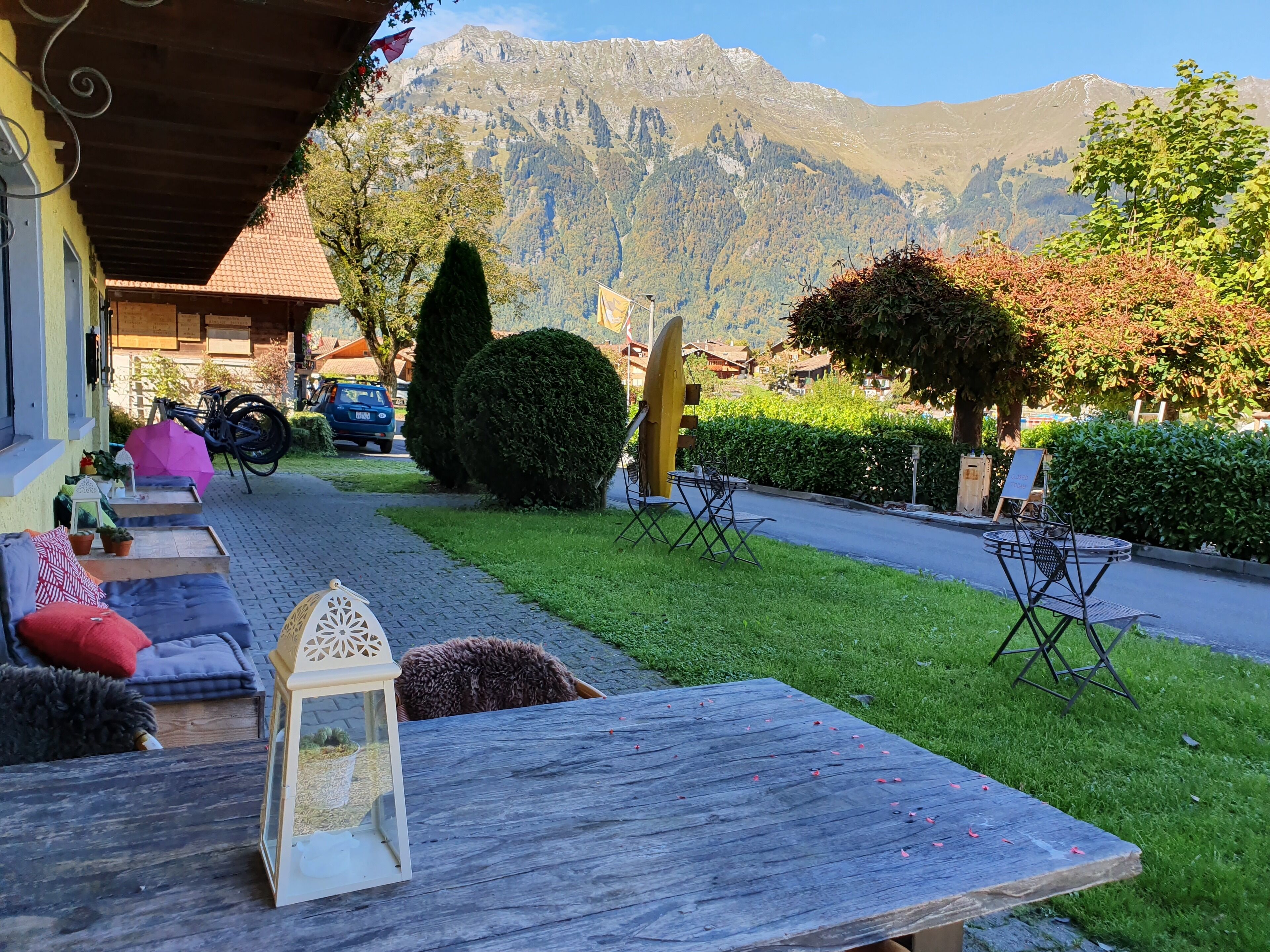Ein gemütlicher Sitzbereich im Freien mit Tisch und Stühlen, einer Laterne und Blick auf Berge im Hintergrund.