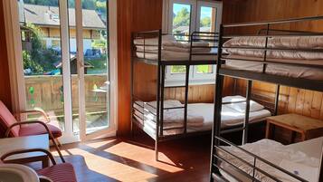 A bunk room with wooden walls, a sliding glass door to a balcony, and a small wooden table.
