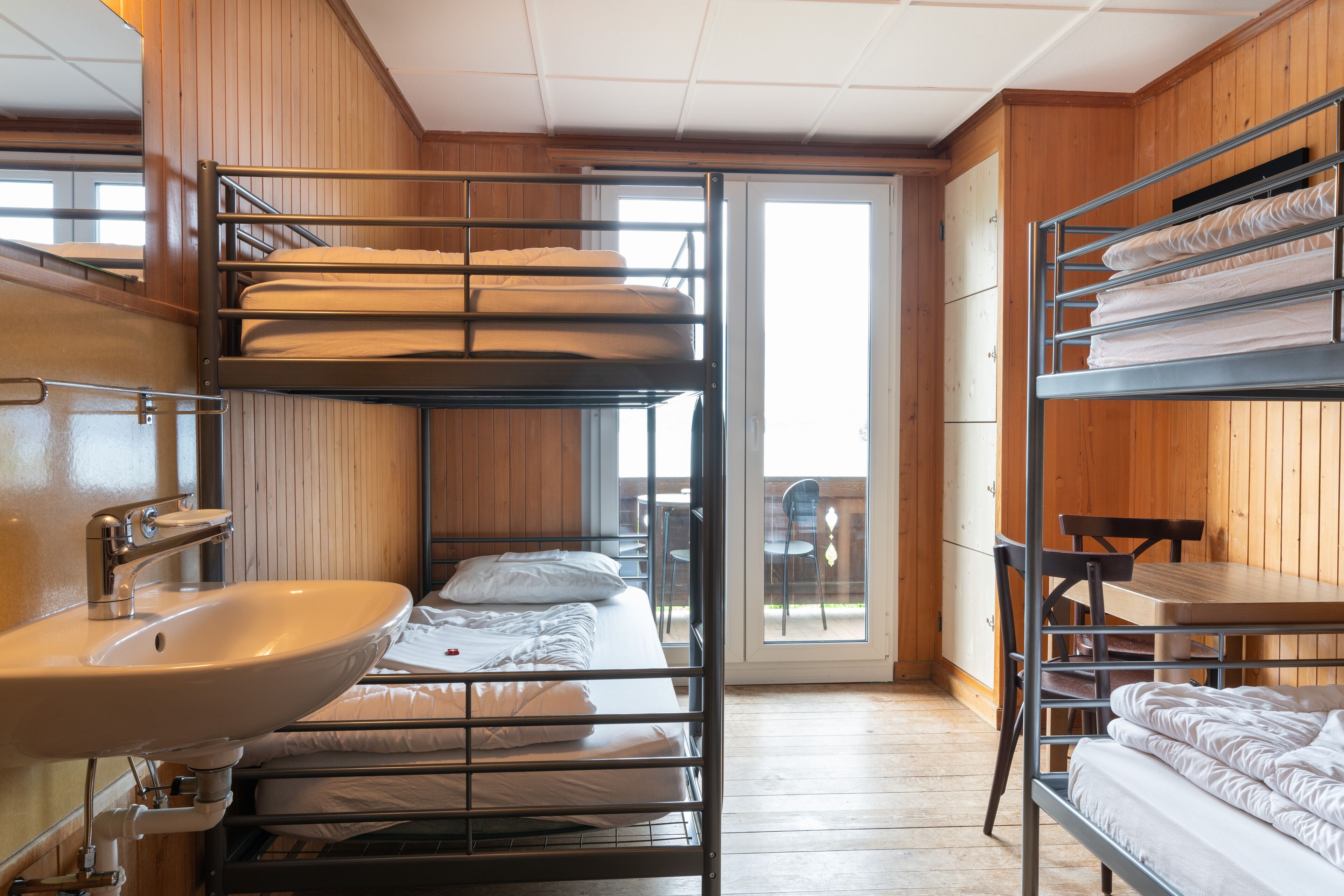 A bunk bed room with a sink and a table.