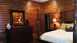 A wooden-paneled bedroom with a four-poster bed, a dresser, and a bench. - High Class Cabin Hideaway (Rutledge)