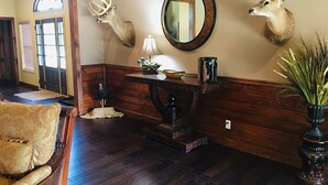 A room with wooden paneling, a mirror, a lamp, a decorative bowl, a vase with plants, and a chair. - High Class Cabin Hideaway (Rutledge)