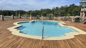 A swimming pool with a wooden deck, surrounded by a stone wall and a metal fence. - High Class Cabin Hideaway (Rutledge)