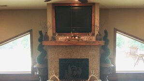 A living room with a fireplace, a television mounted above it, and two large windows on either side. - High Class Cabin Hideaway (Rutledge)