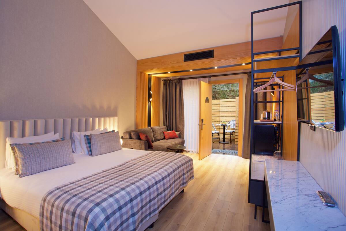A modern hotel room with a large bed, a desk, and a seating area with a sofa and chairs.
