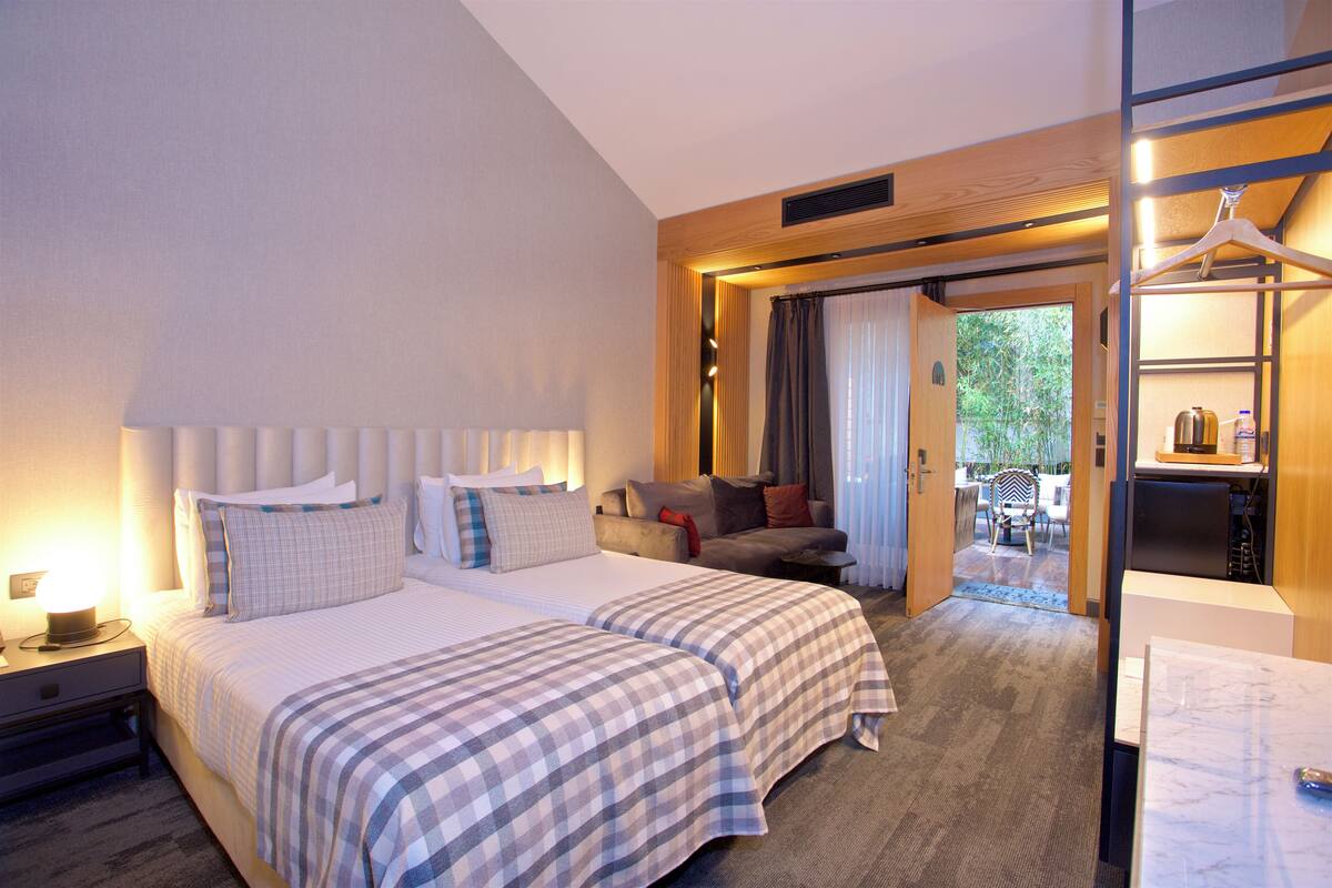 A hotel room with a large bed, a sofa, a desk, and a view of the outdoors.