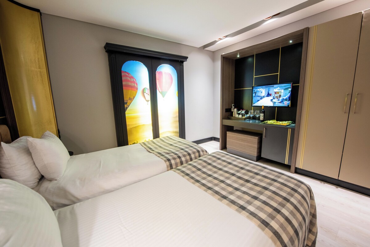 A hotel room with a bed, a desk with a TV, and a wardrobe.