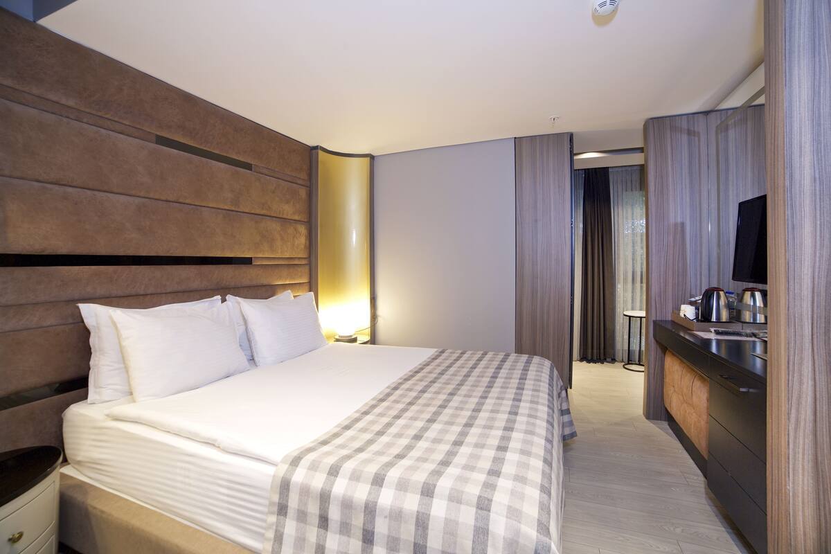 A hotel room with a bed, bedside table, and a built-in TV.