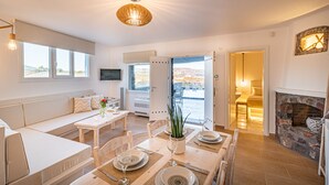 Un comedor moderno con una mesa de madera dispuesta para cuatro personas, un sofá y una chimenea.