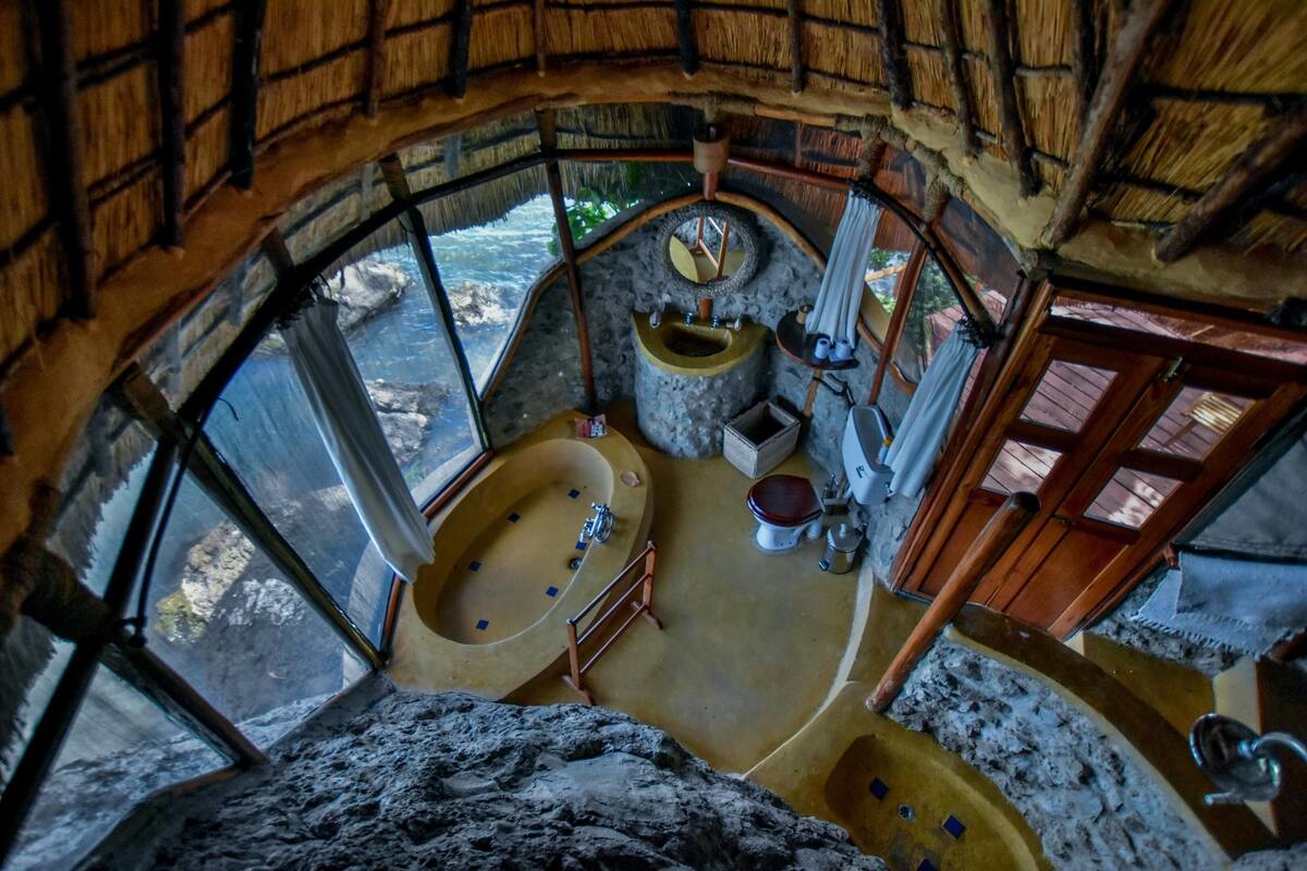 A circular bathroom with a stone sink, a bathtub, and a toilet.