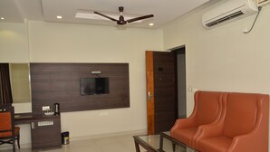 A modern living room with a flat-screen TV, a sofa, a coffee table, and a ceiling fan. - Hotel KK Continental (Amritsar)