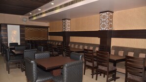 A restaurant with booths and tables, some with cushioned seats. - Hotel KK Continental (Amritsar)