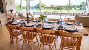 A dining area with a large table set for six, surrounded by wooden chairs. - Wonderful Spacious Family Home in Constantine Bay Situated on Road to Beach (Constantine Bay)