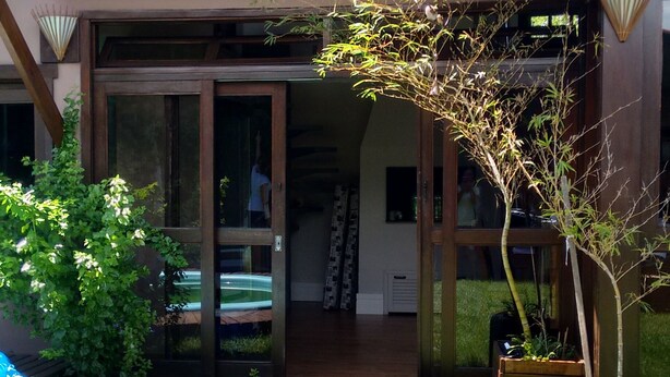 Una casa amb un porxo cobert, un terraç de fusta i un jardí amb gespa on hi ha passos que porten a l'entrada.