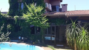 Una casa amb piscina, envoltada de vegetació i amb teulada de rajola.