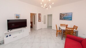 Una sala de estar moderna con un televisor de pantalla plana, un comedor con sillas de madera y un sofá rojo.