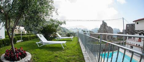 Ein Poolbereich auf dem Dach mit Liegestühlen und Blick auf die Stadt.