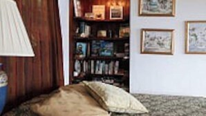 A room with a wooden floor, a sofa, a lamp, and a bookshelf with framed pictures. - Casa Sack Ocean Front apartment  (Rincon)