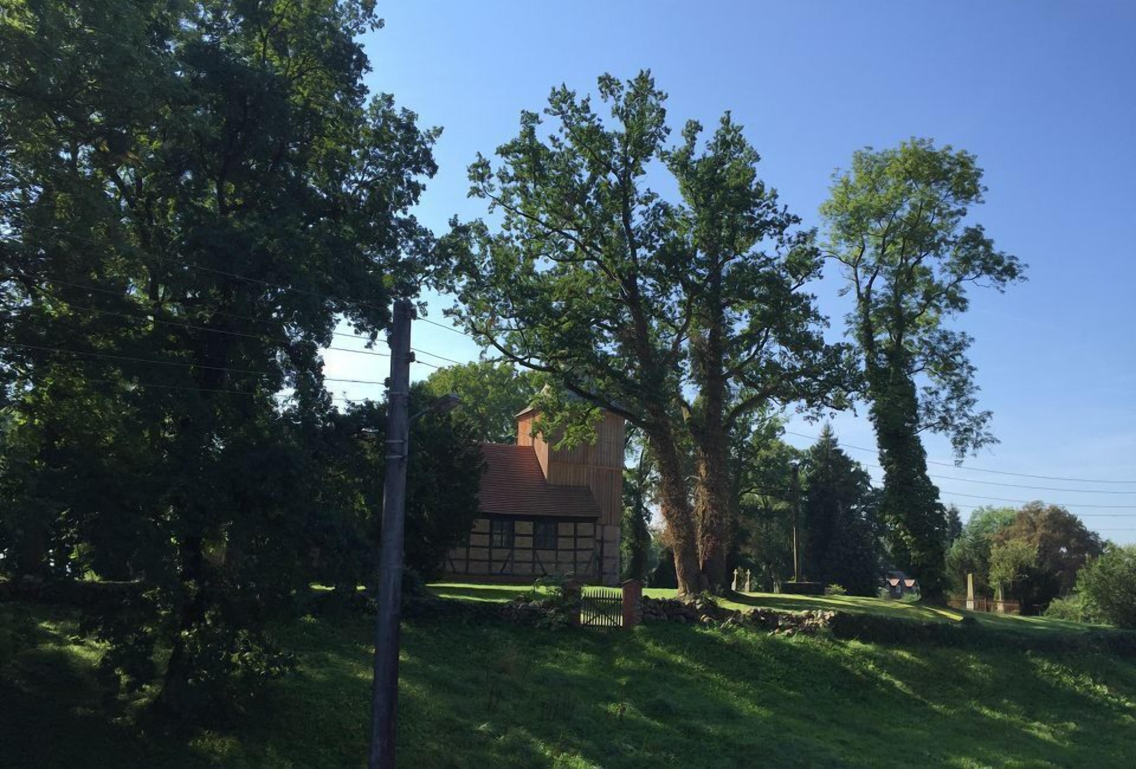 A traditional house with a sloped roof, surrounded by lush green trees and a well-maintained lawn.