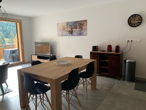 Enjoy meals in this dining area with a view of the surrounding forest, featuring a wooden table and comfortable seating.