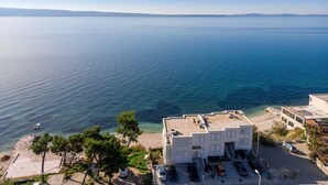 A coastal building with a parking area and a view of the sea. - Tanita Beachfront Penthouse (Podstrana)