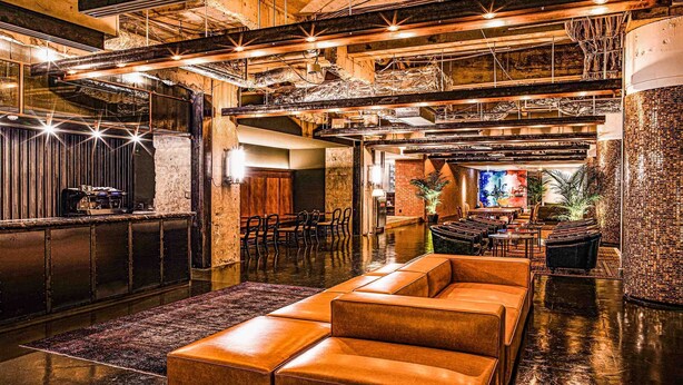 A spacious lobby with a bar area, leather seating, and a high ceiling with exposed beams. - The Steel House (Kitakyushu)