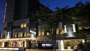 A modern hotel with a prominent 'THE STEEL HOUSE' sign, large windows, and a well-lit entrance area. - The Steel House (Kitakyushu)