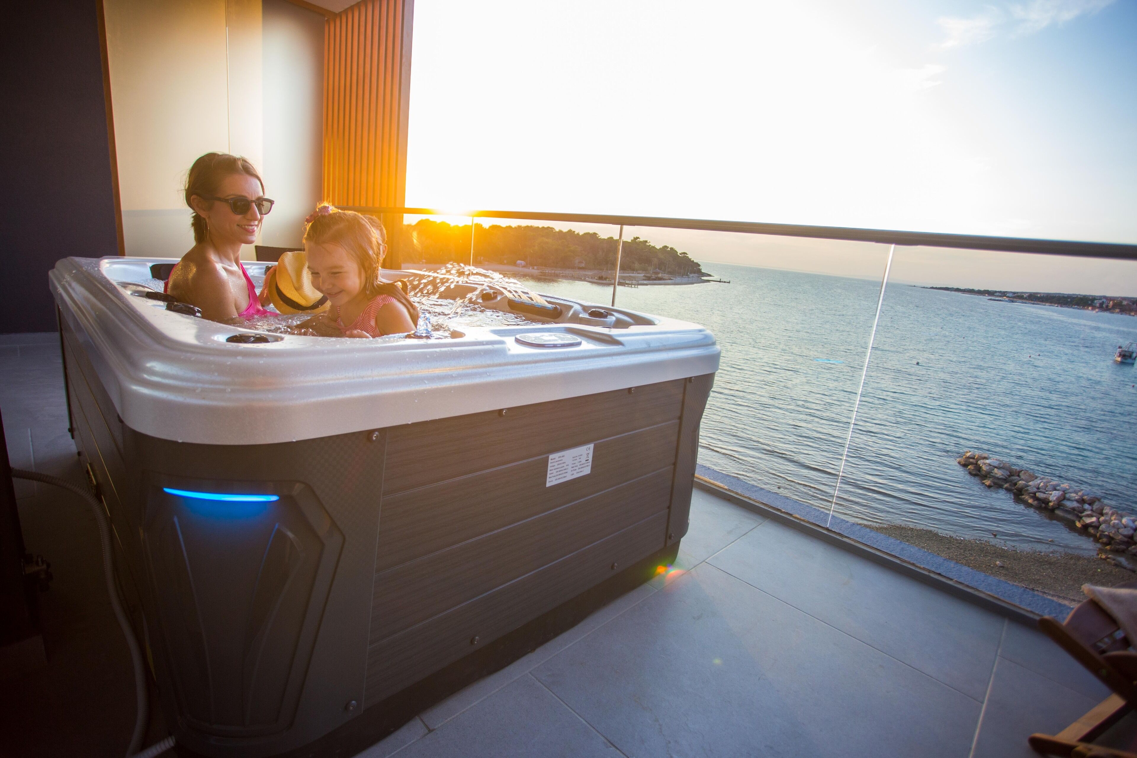 A hot tub with a view of the sea and a sunset.