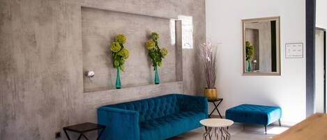 Ein modernes Interieur mit einem türkisfarbenen Sofa, einem kleinen runden Tisch und einem blauen Hocker.