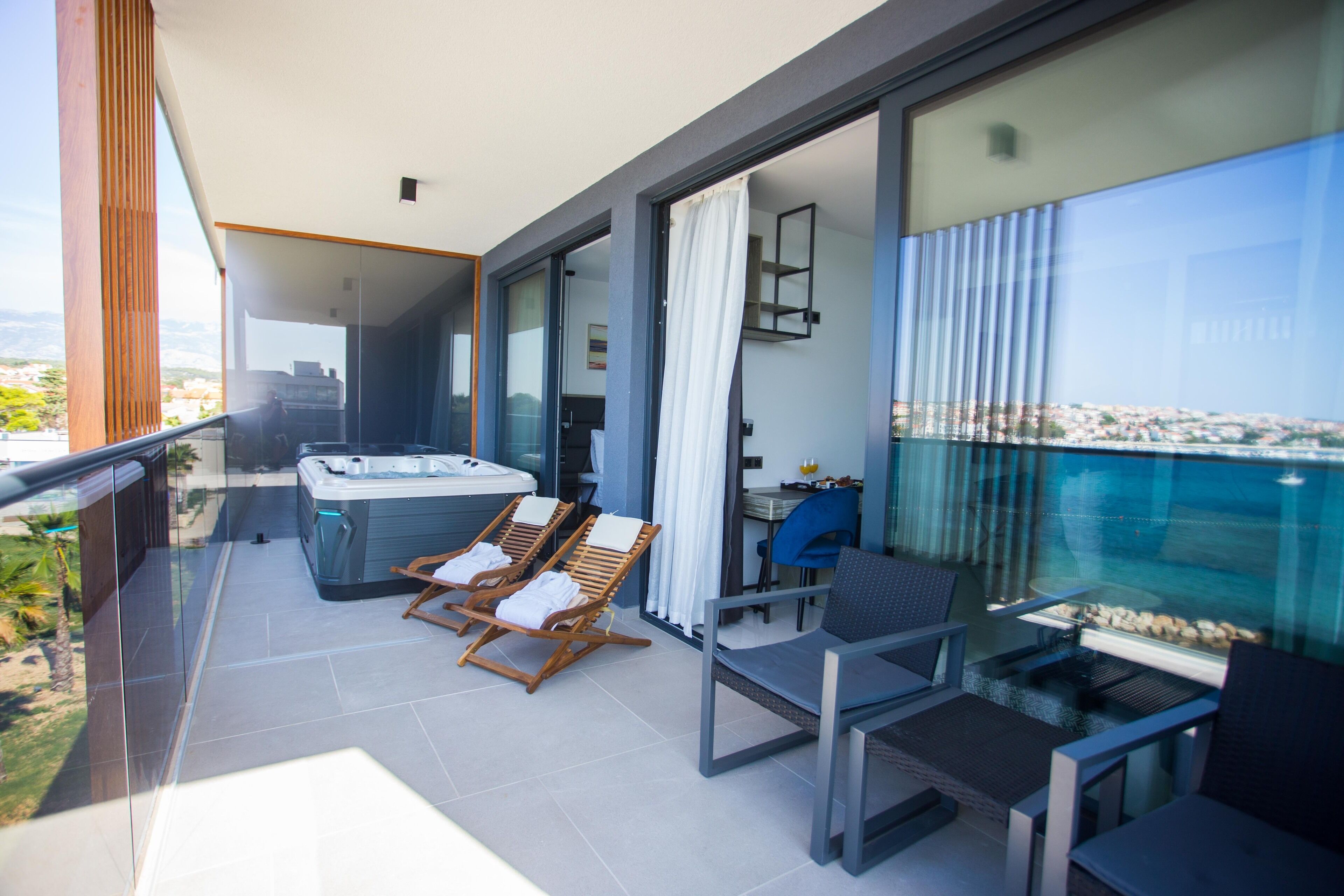 A balcony with a hot tub, lounge chairs, and a table with chairs.