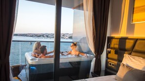 Una stanza con un'ampia finestra vista su un corpo d'acqua, un letto con biancheria dai motivi decorativi e una moderna testiera.