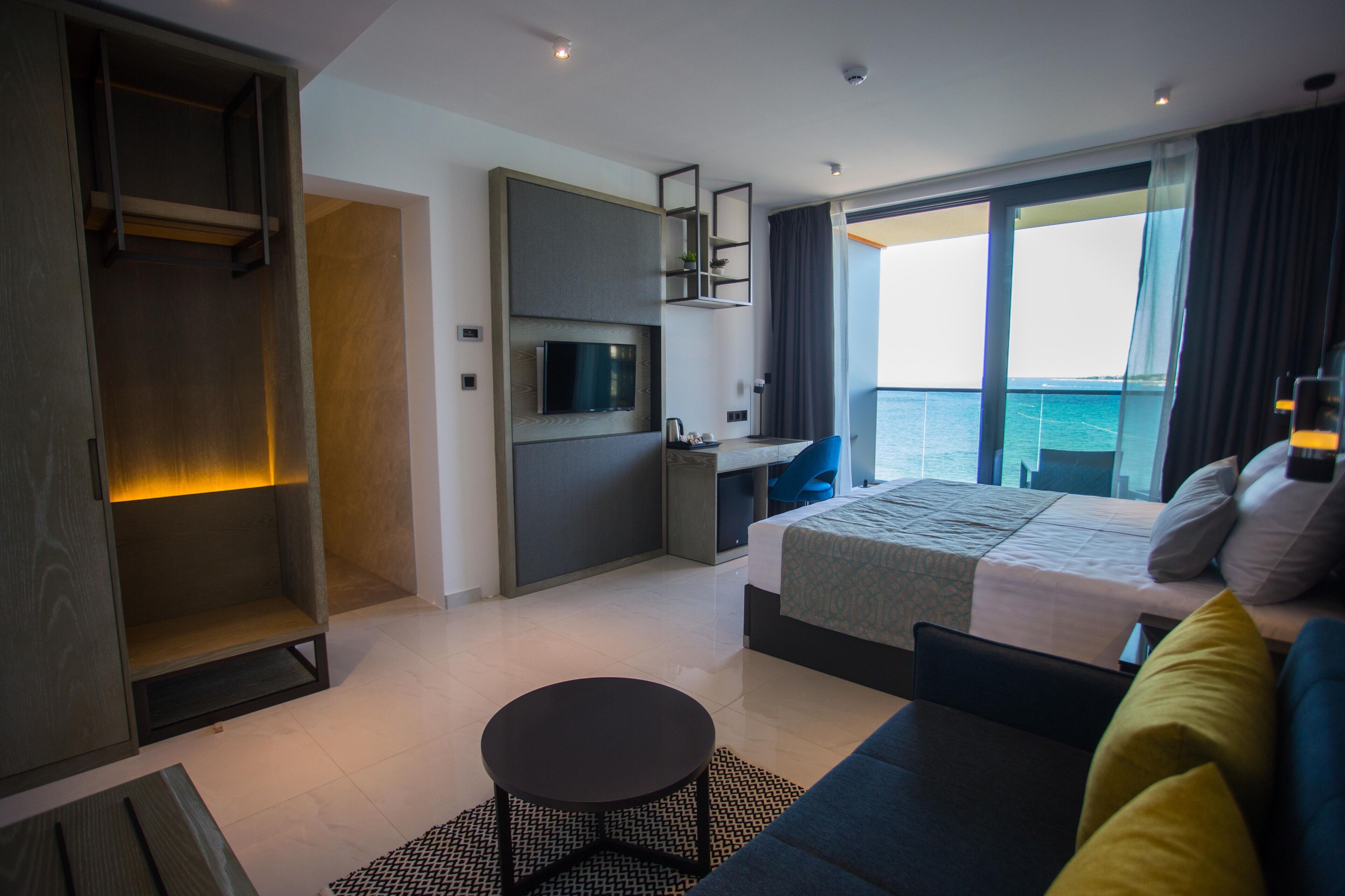 Una habitación de hotel moderna con cama, escritorio, televisión y vista al mar.