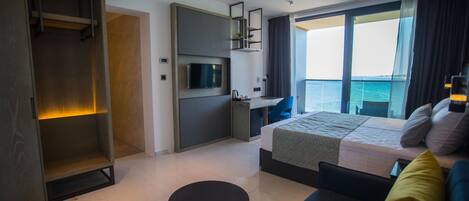 Una habitación de hotel moderna con cama, escritorio, televisión y vista al mar.
