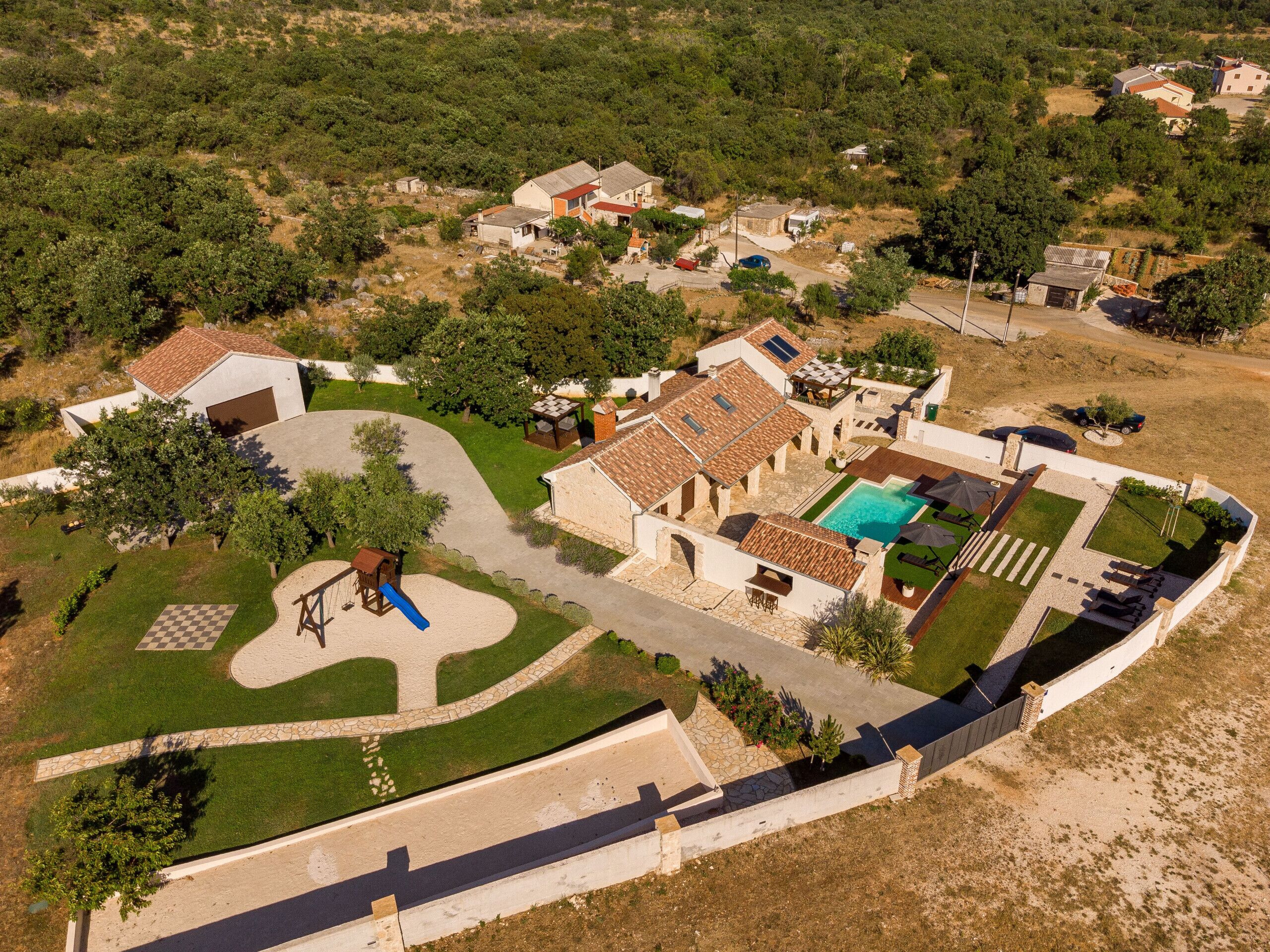 Vista aérea de una zona residencial con casas, piscina y parque infantil.