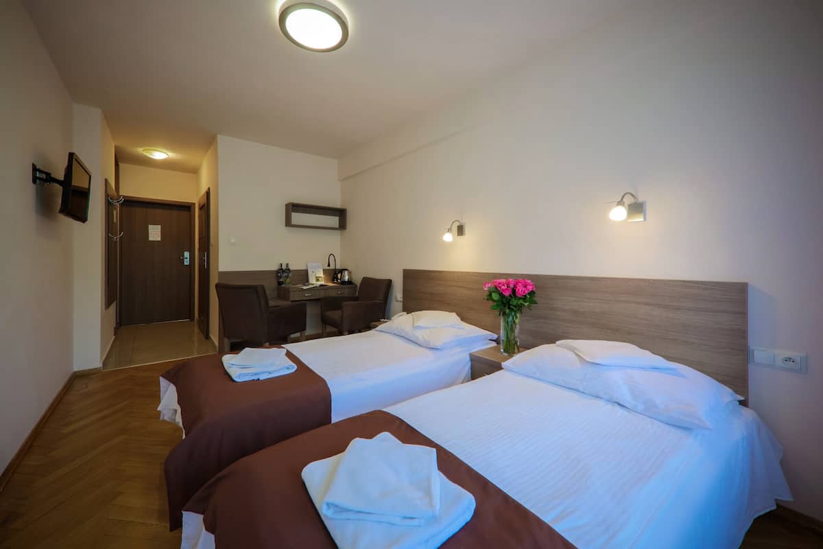 Ein Hotelzimmer mit zwei Betten, einem Schreibtisch und einer Dusche.