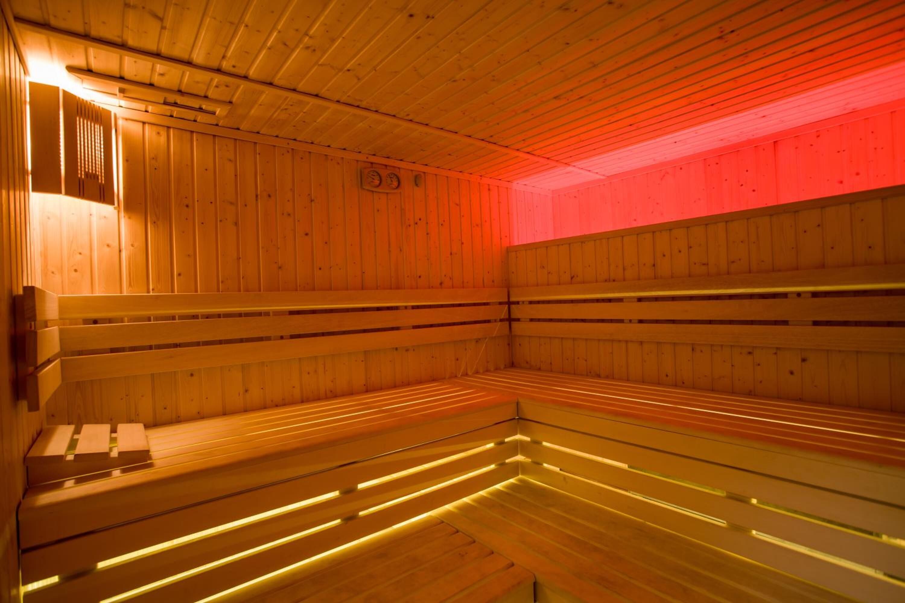 A sauna with wooden benches and a red light.